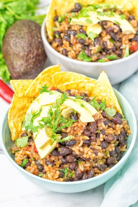 two Vegetarian BBQ Burrito Bowls garnished with avocado slices.