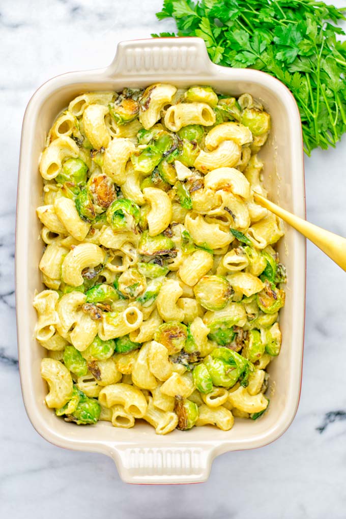 This Garlic Brussels Sprouts Mac and Cheese is entirely vegan, gluten free, and super easy to make. It's an amazing comfort food for dinner, lunch, meal prep, work lunches, date nights and of course the holidays. Everyone will get addicted to this from the first to the last bite, try it now! #vegan #glutenfree #dairyfree #vegetarian #mealprep #dinner #lunch #worklunchideas #holidays #macandcheese #contentednesscooking #pasta #thanksgiving
