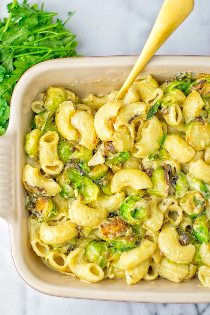 This Garlic Brussels Sprouts Mac and Cheese is entirely vegan, gluten free, and super easy to make. It's an amazing comfort food for dinner, lunch, meal prep, work lunches, date nights and of course the holidays. Everyone will get addicted to this from the first to the last bite, try it now! #vegan #glutenfree #dairyfree #vegetarian #mealprep #dinner #lunch #worklunchideas #holidays #macandcheese #contentednesscooking #pasta #thanksgiving