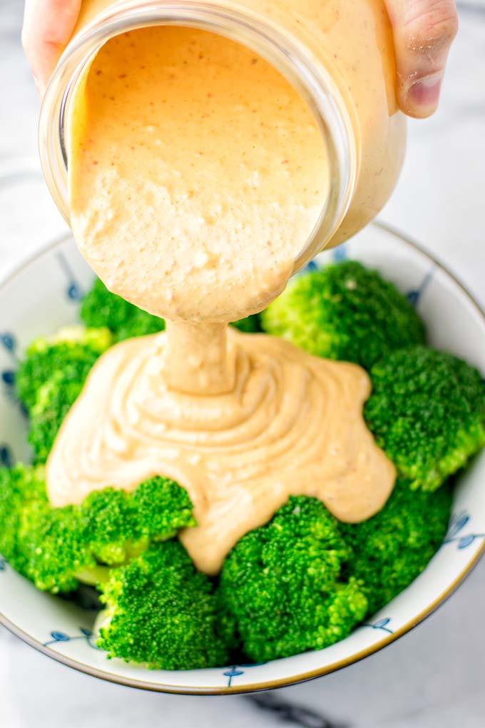 Thai peanut sauce poured over a bowl with broccoli.