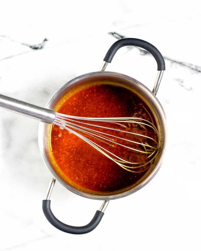 Top view on the metallic saucepan with the ready Nashville Hot Sauce and a wire whisk inside.