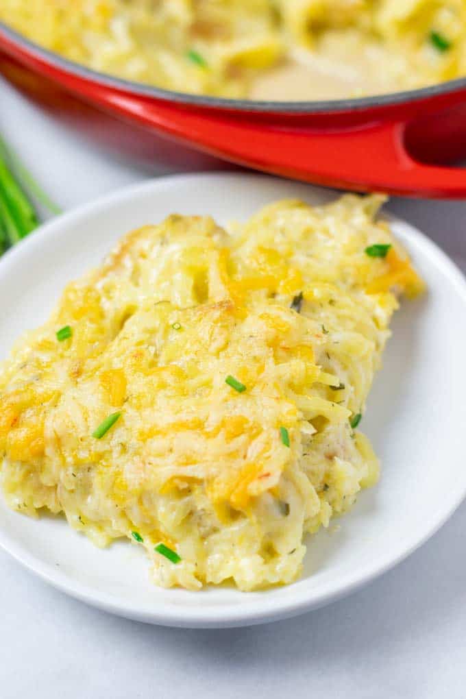Closeup of a portion of the Hashbrown Potatoes on a white plate with the casserole dish in the background.