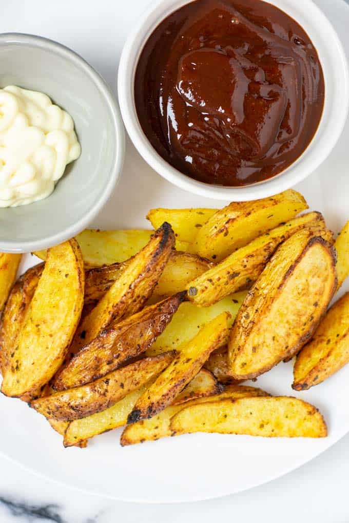 A serving of the Potato Wedges on a plate with mayo and ketchup.