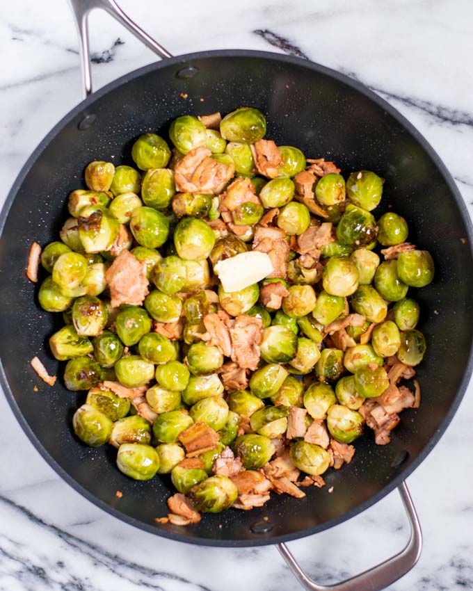 Mixed Bacon Brussels sprouts in a pan with a slice of butter.