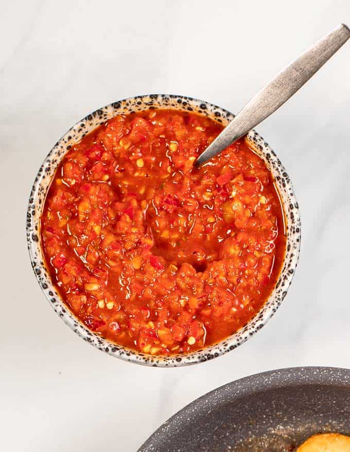 Closeup of a serving bowl with Peri Peri Sauce with a small spoon.