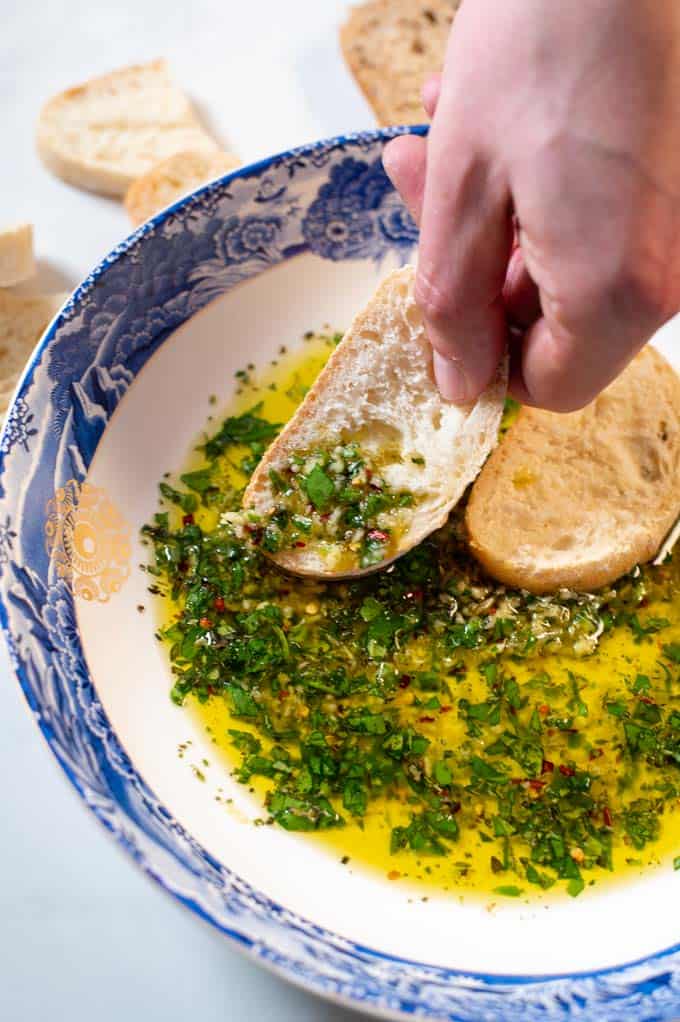 Bread dipped in oil is held by a hand.
