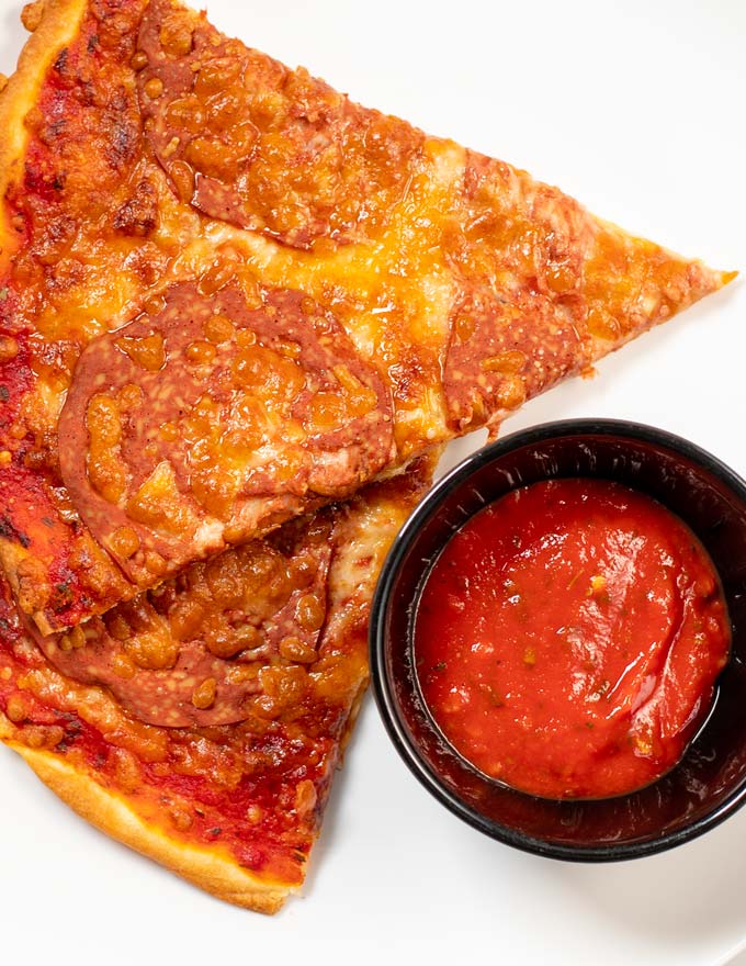 Closeup on two slices of homemade pizza with extra Pizza Sauce.