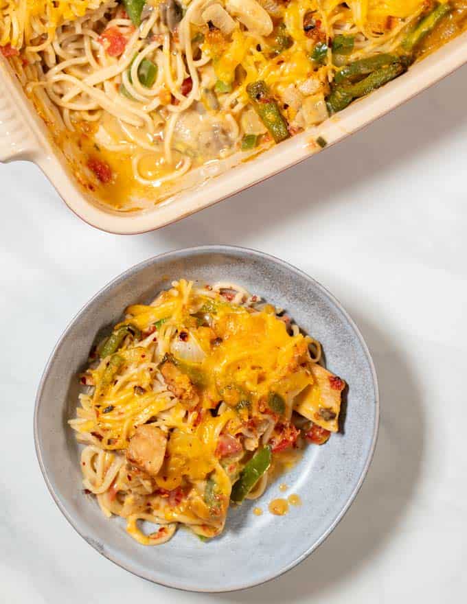 A portion of Texas Chicken Casserole is served on a plate with the casserole dish in the background.