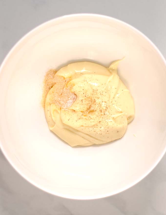 The tangy dressing is made in a while bowl.