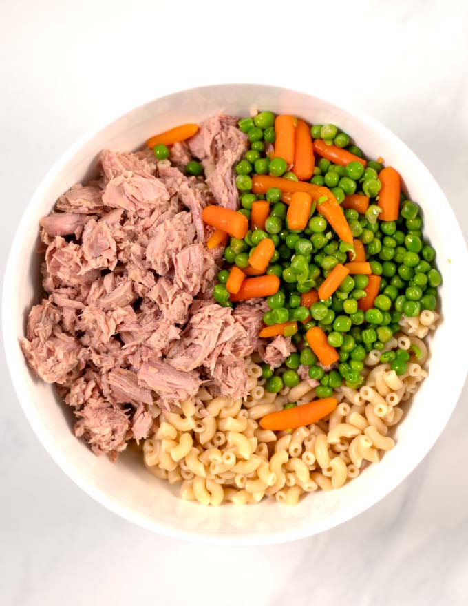 Salad ingredients are added to the white bowl with the dressing.