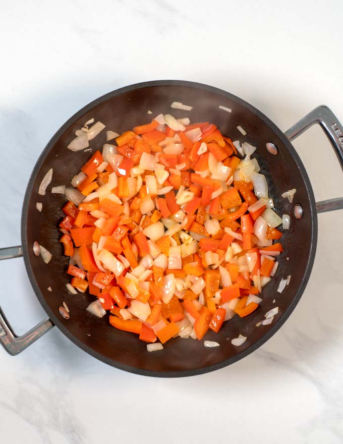 Top view on a pan with frying onions and bell pepper.