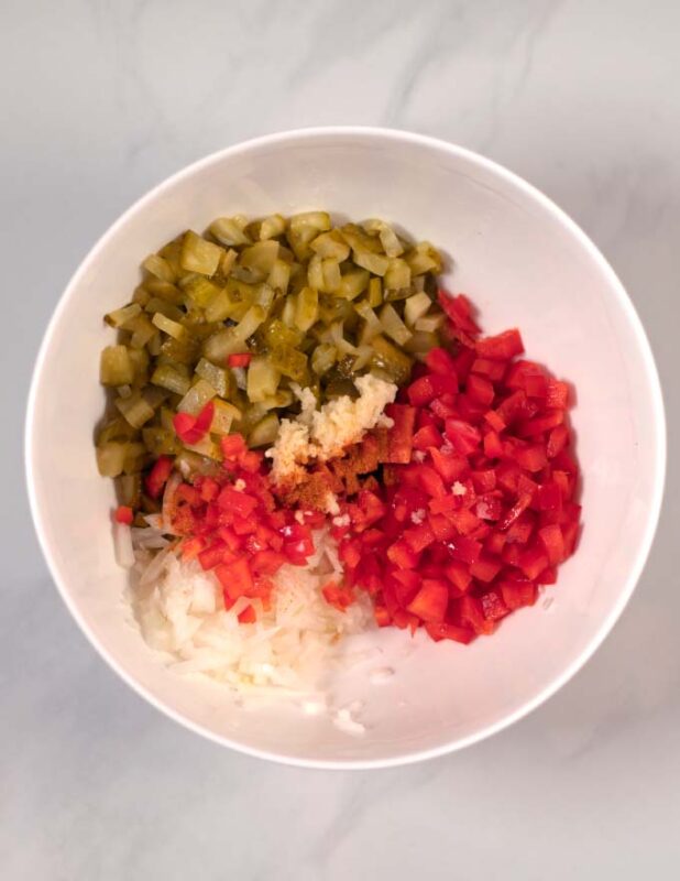 View of a large white mixing bowl with the chopped ingredients for Pickle de Gallo.