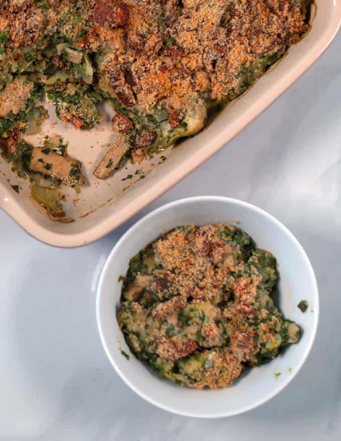 A serving of Chicken Artichoke Casserole with baking dish in the background.