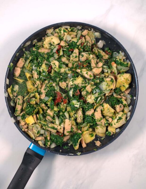 Spinach and sun-dried tomatoes have been added to the pan.