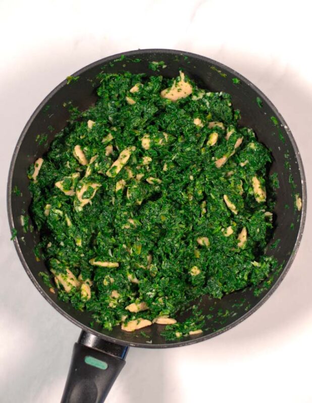 Vegan chicken and spinach are fried in a pan.