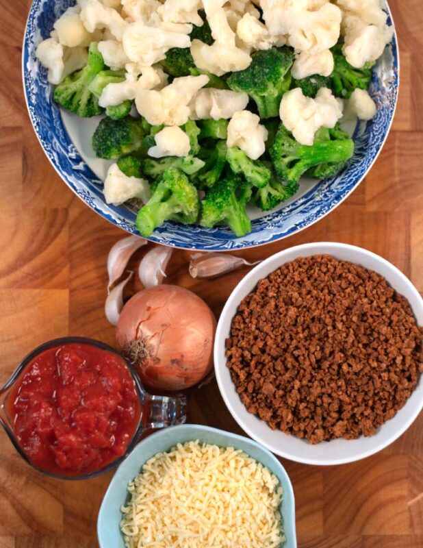 Ingredients needed to make Keto Broccoli Cauliflower Casserole collected on a board.