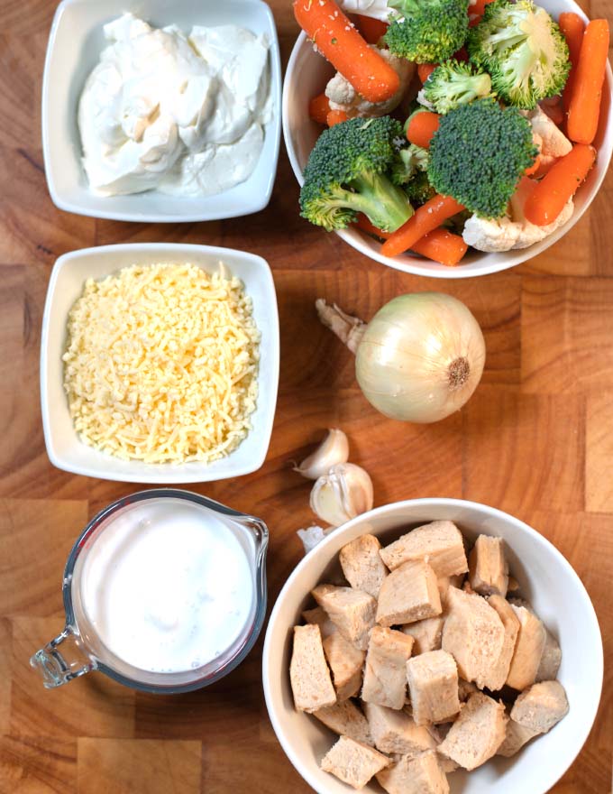 Ingredients needed to make Keto Chicken Vegetable Casserole on a wooden board.