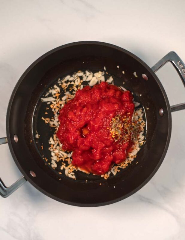 Diced tomatoes and spices are added to the garlic.