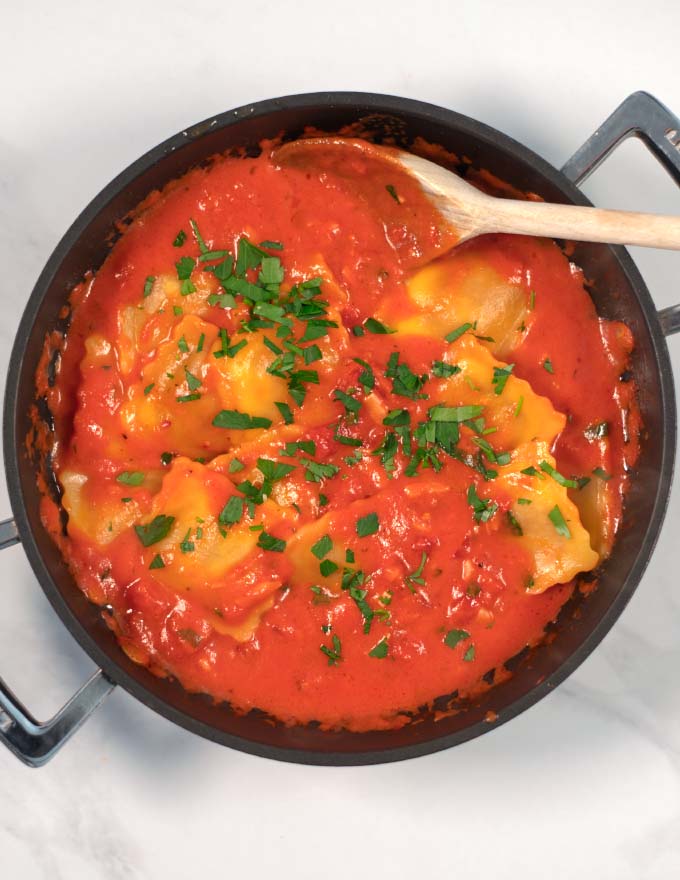 A large serving of ravioli in sauce, garnished with fresh parsley.