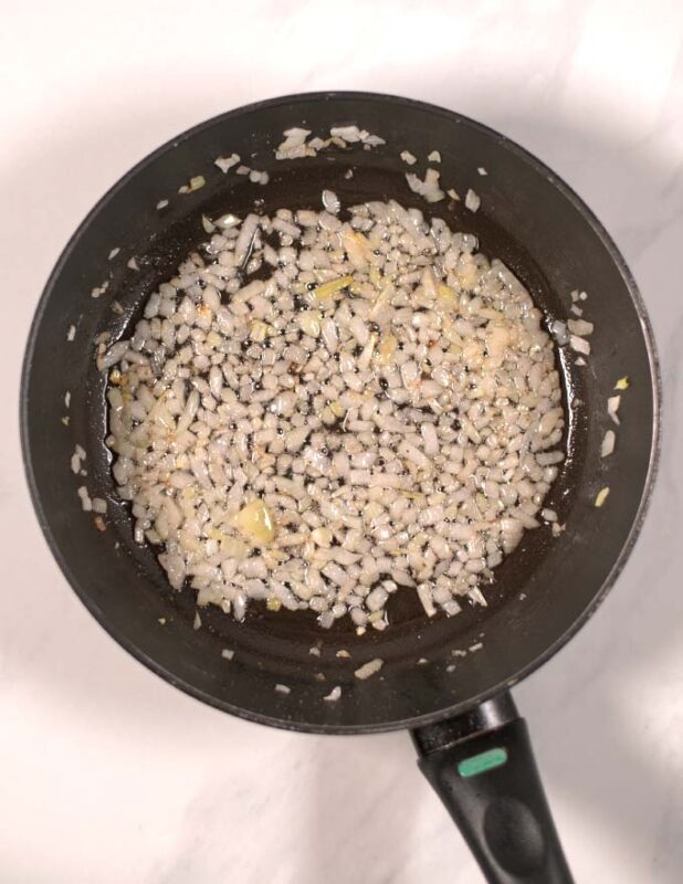 Diced onions are sauteed in a pan.