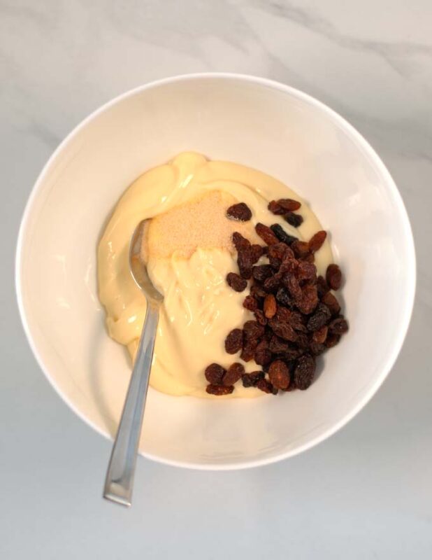 Mayo, spices, and raisins are combined in a large bowl.
