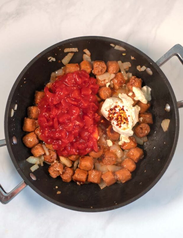 Diced tomatoes, dairy-free sour cream and chili flakes are added to the pan.