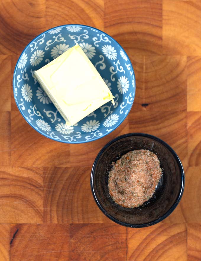 Ingredients needed to make Cajun Garlic Butter Sauce are collected on a wooden board.