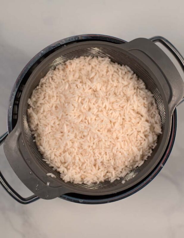 Freshly cooked rice in a colander.