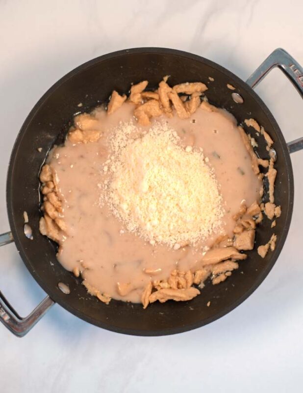 Cream of mushroom soup and vegan parmesan are added to the pan with the fried chicken.