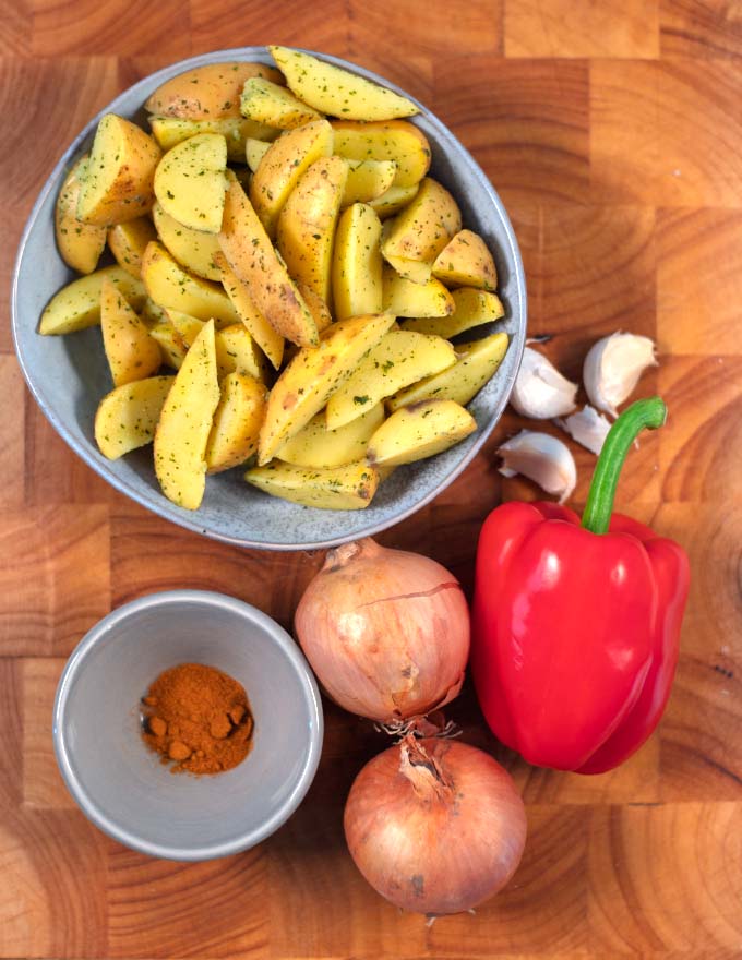 Ingredients needded to make Potatoes with Peppers and Onions are collected on a board.