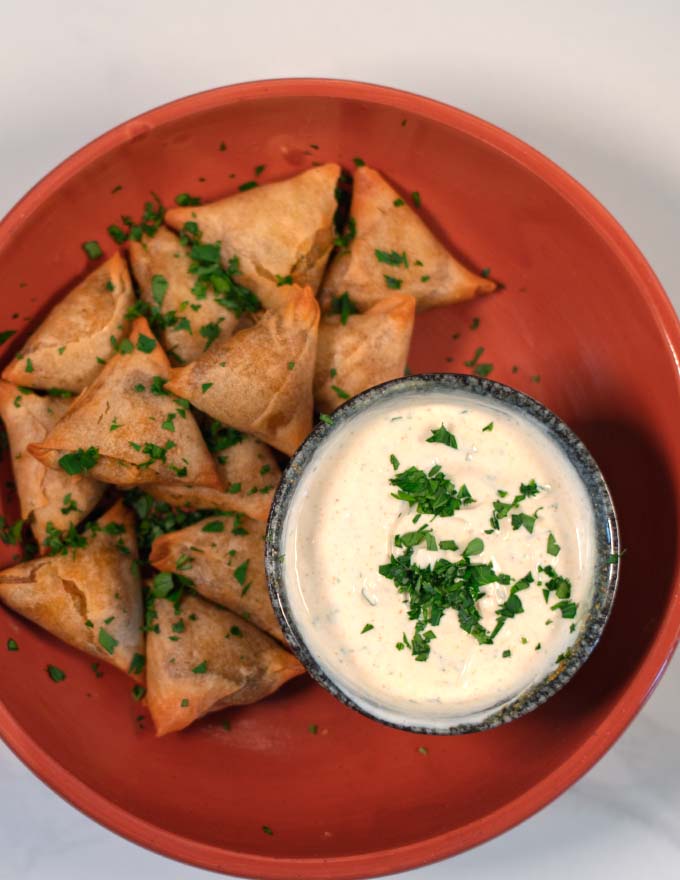 Serving of samosas with sauce.