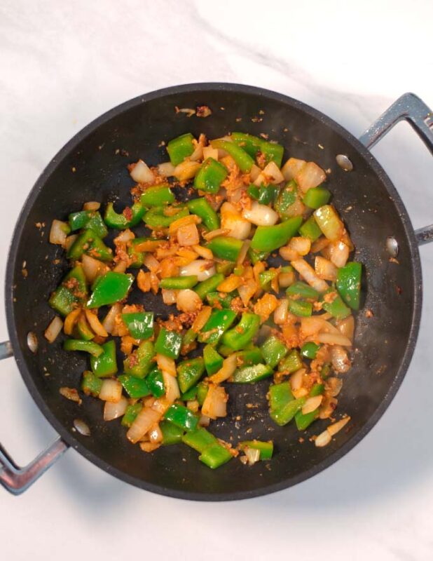 Bell pepper and onions are fried in a pan.