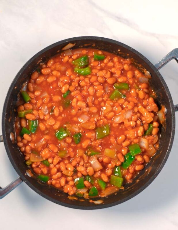 White beans and tomato sauce are added to the pan.