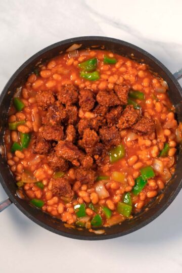 Browned sausage bits are given to the bean chili.