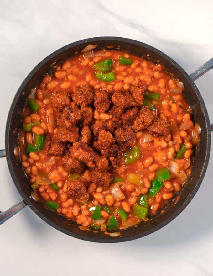 Browned sausage bits are given to the bean chili.