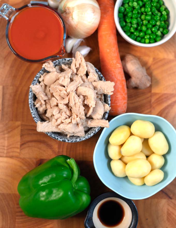 Ingredients needed for making Afritada Chicken collected on a wooden board.
