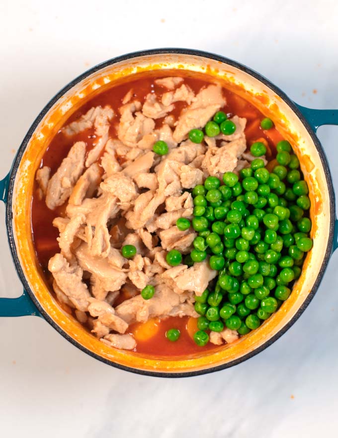 The pre-cooked chicken and peas are added to the Afritada.