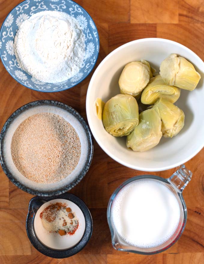 Ingredients needed to make Fried Artichokes are collected on a board.