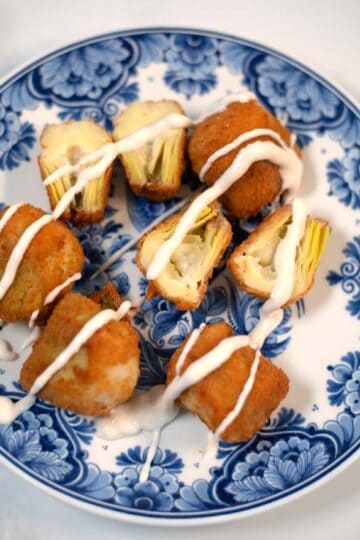 A plate of fried artichoke hearts sprinkled with sauce.