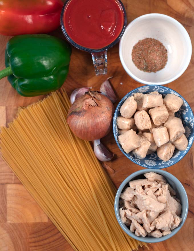 Ingredients needed for making Jambalaya Pasta are collected on a wooden board.