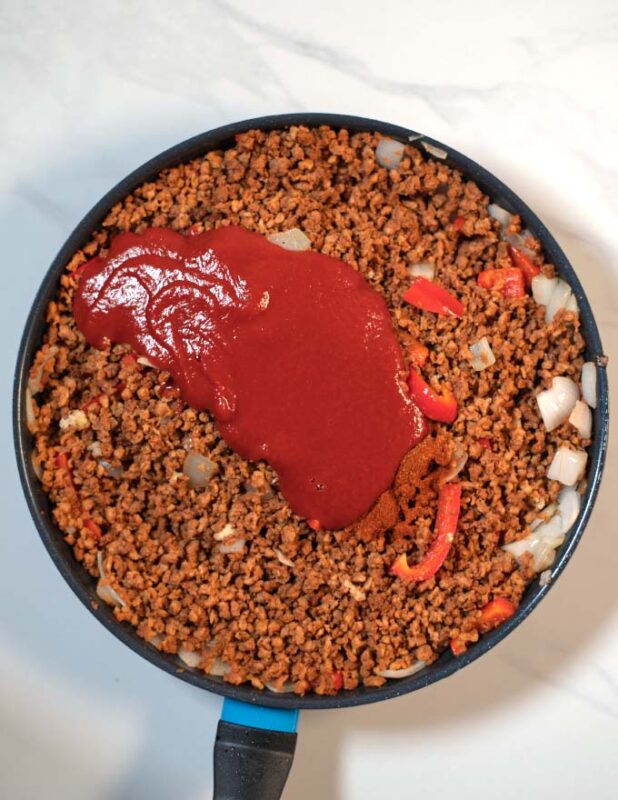 Tomato sauce and seasonings are mixed with the cooked vegan ground beef.