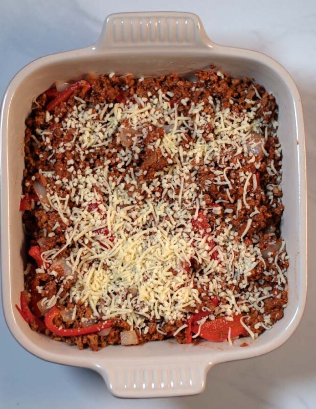 Vegan cheese is used to top the Keto Sloppy Joe Casserole in a baking dish.