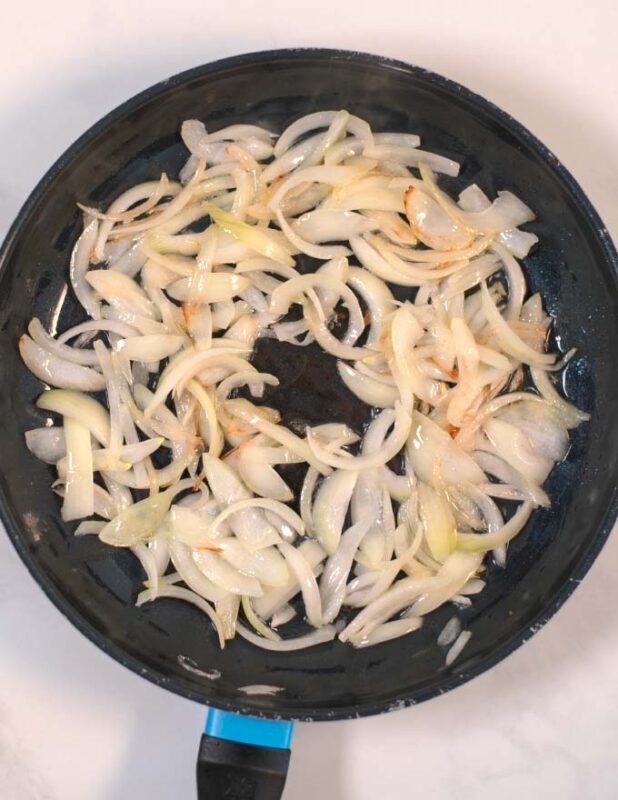 Onions are fried in a pan.