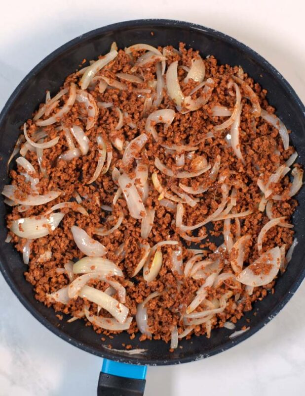 Vegan ground beef is added to the pan with the onions.