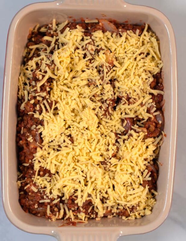 Baking dish with Lentil Casserole topped with vegan cheese before baking.