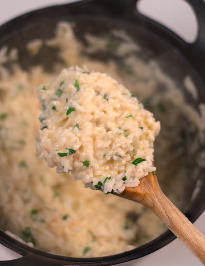 A large spoon of Parmesan Rice lifted from the pot.
