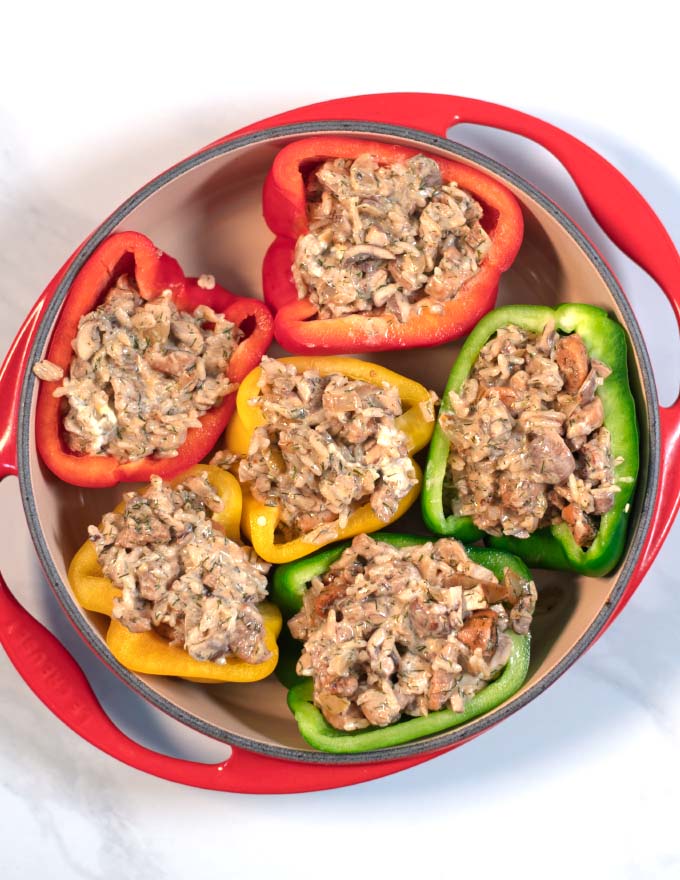 Halved bell peppers in a baking dish are filled with the stuffing.