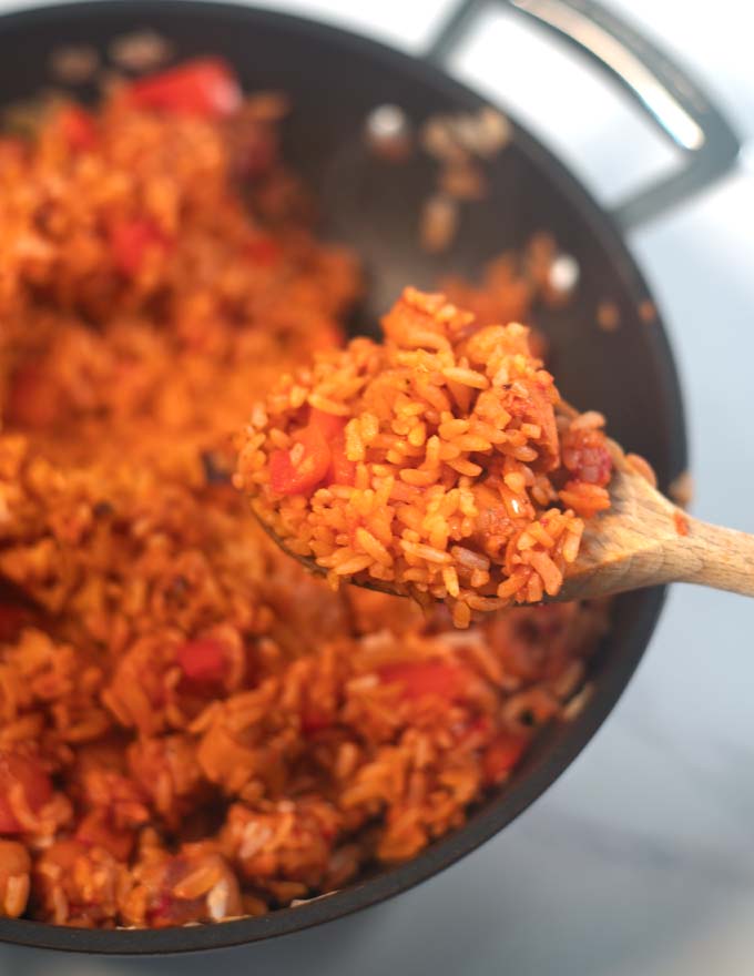 A spoonful of Smoked Sausage and Rice is lifted from the pan.