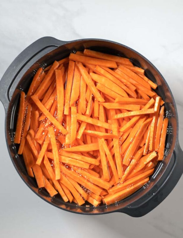 Perfectly cut sweet potato frries are washed in water.