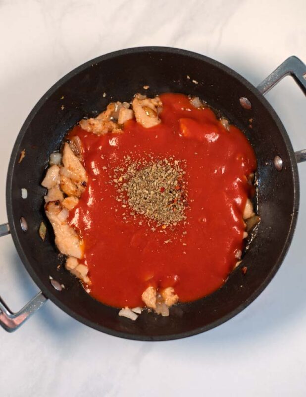 Tomato sauce and spices are given to the pan.